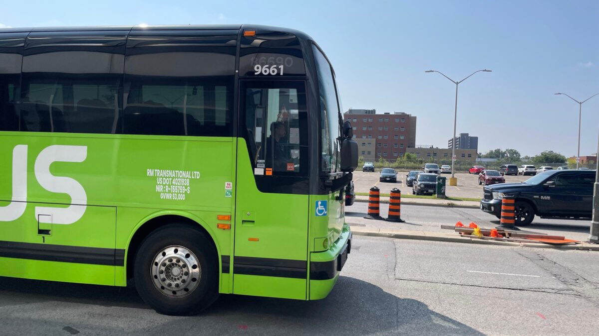 Lime green Flixbus branded motorcoach passing road works.